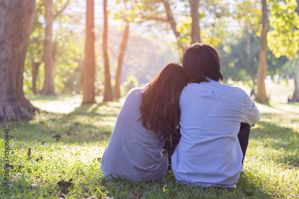 Valentine couple sit on grass in garden while sunset. Valentine couple sit on grass in garden while sunset.