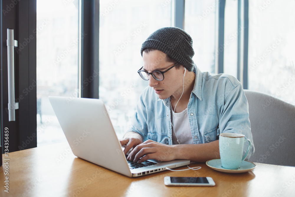Handsome businessman in casual wear and eyeglasses is using a laptop in cafe Handsome businessman in casual wear and eyeglasses is using a laptop in cafe