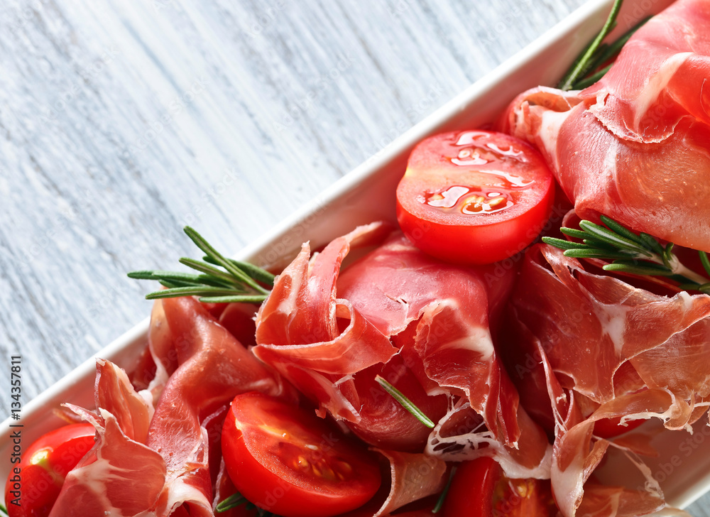  Prosciutto with  rosemary and tomato on a wooden table