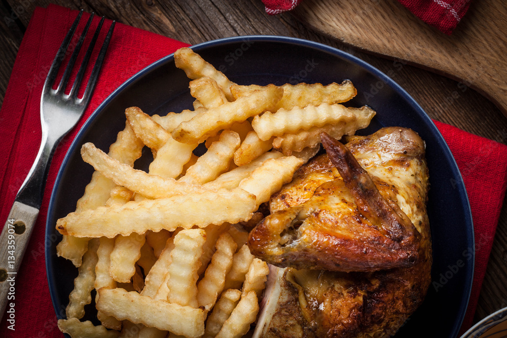 Roasted chicken with french fries on a plate.