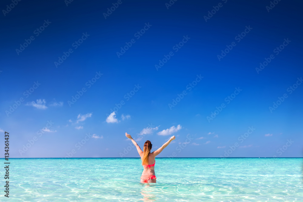 Beautiful young woman standing in the ocean with hands raised. Maldives Beautiful young woman standing in the ocean with hands raised. Maldives