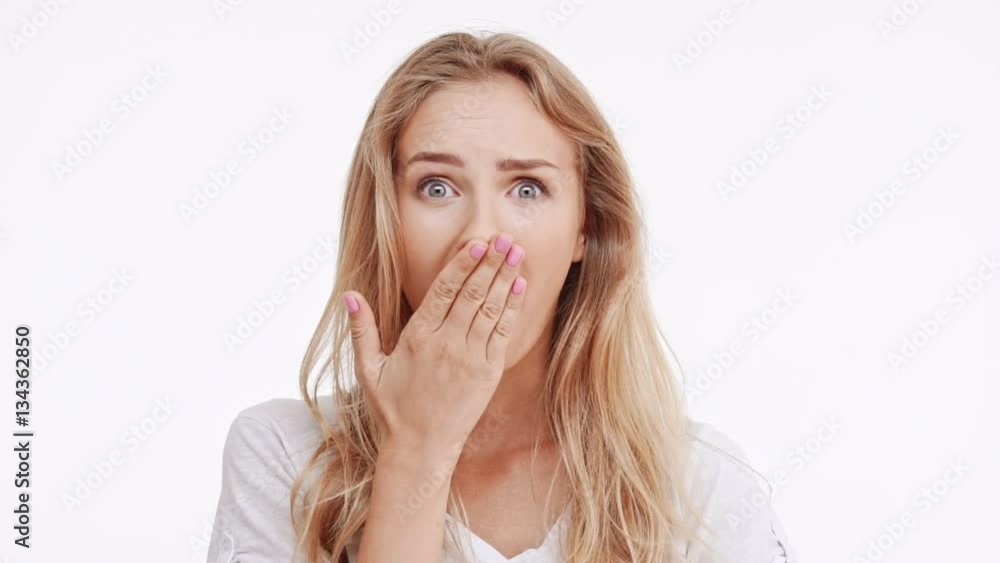 Young beautiful Caucasian blonde girl suspiciously moving eyes then remebers something and surprises on white background in slowmotion Young beautiful Caucasian blonde girl suspiciously moving eyes then remebers something and surprises on white background in slowmotion