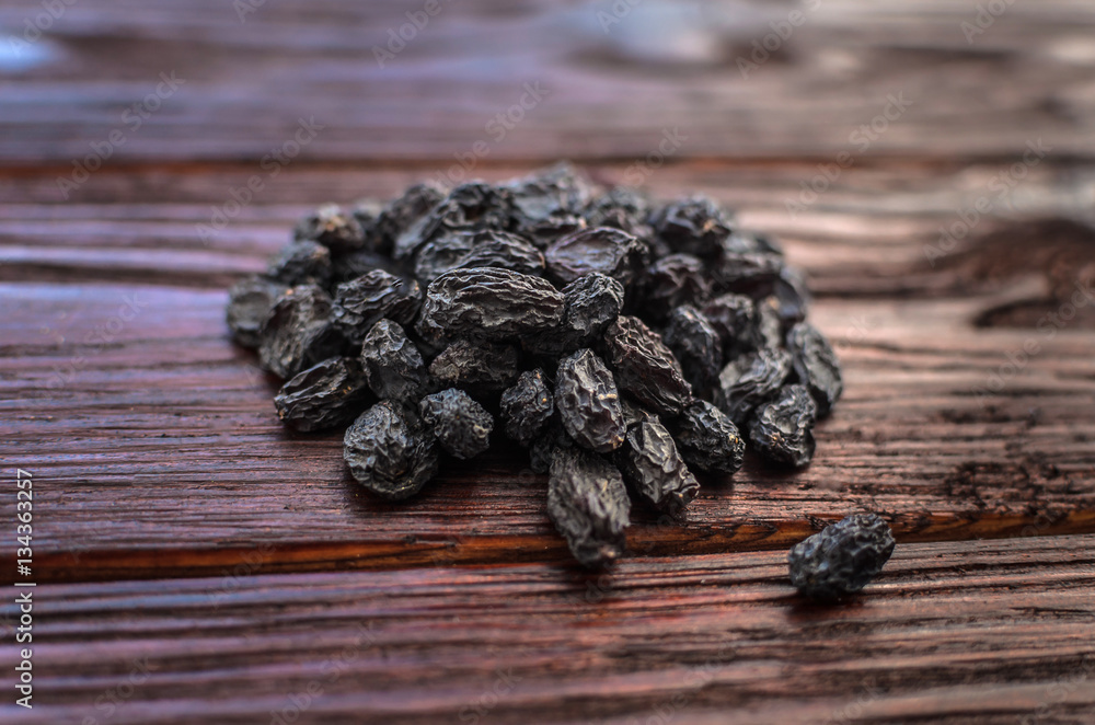 Dark dried grapes (raisins) on a texture wooden table Dark dried grapes (raisins) on a texture wooden table