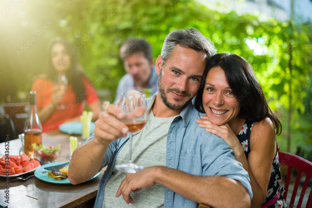 Fototapeta premium portrait of a couple, they sit with friends around a table