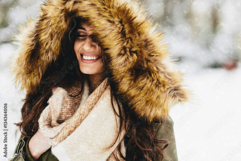 Young woman with a fur hood in the park on the snow Young woman with a fur hood in the park on the snow