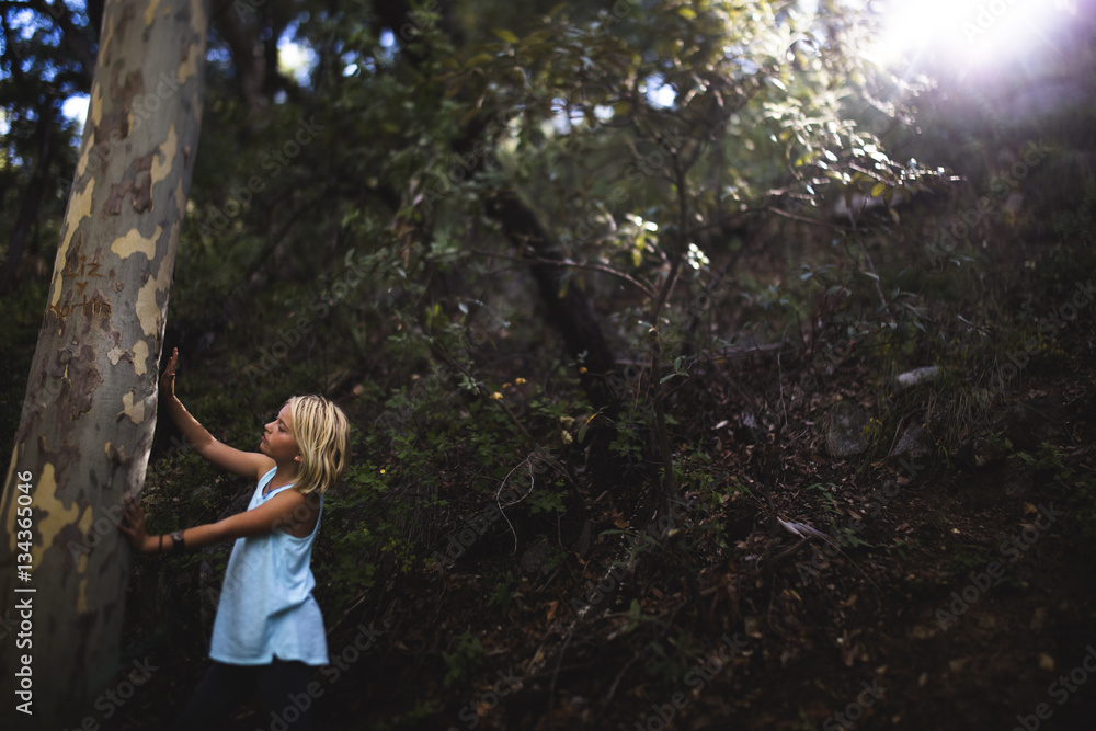 Girl touching tree trunk in forest Girl touching tree trunk in forest