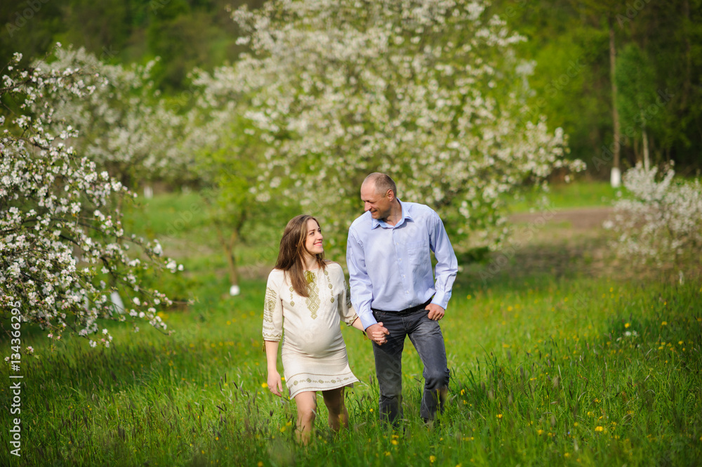 pregnant woman with husband in blooming garden pregnant woman with husband in blooming garden