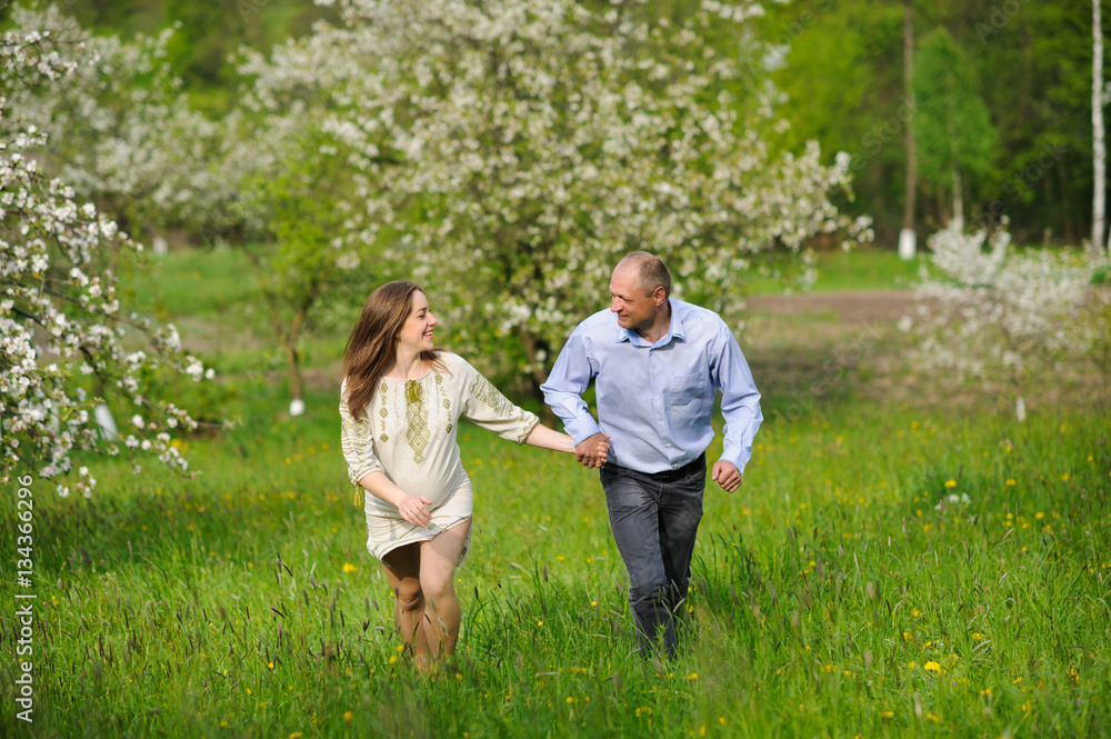 pregnant woman with husband  in blooming garden