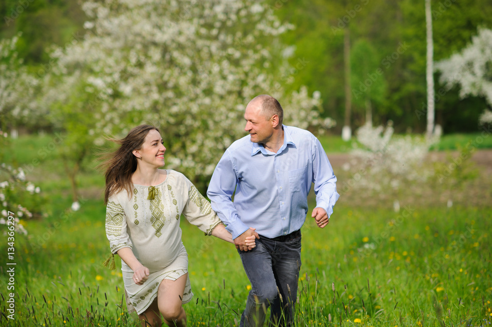 pregnant woman with husband in blooming garden pregnant woman with husband in blooming garden