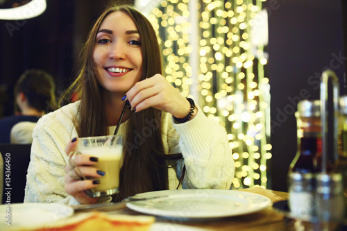 Beautiful young woman drinking coffee at cafe. Tonned. Selective focus.