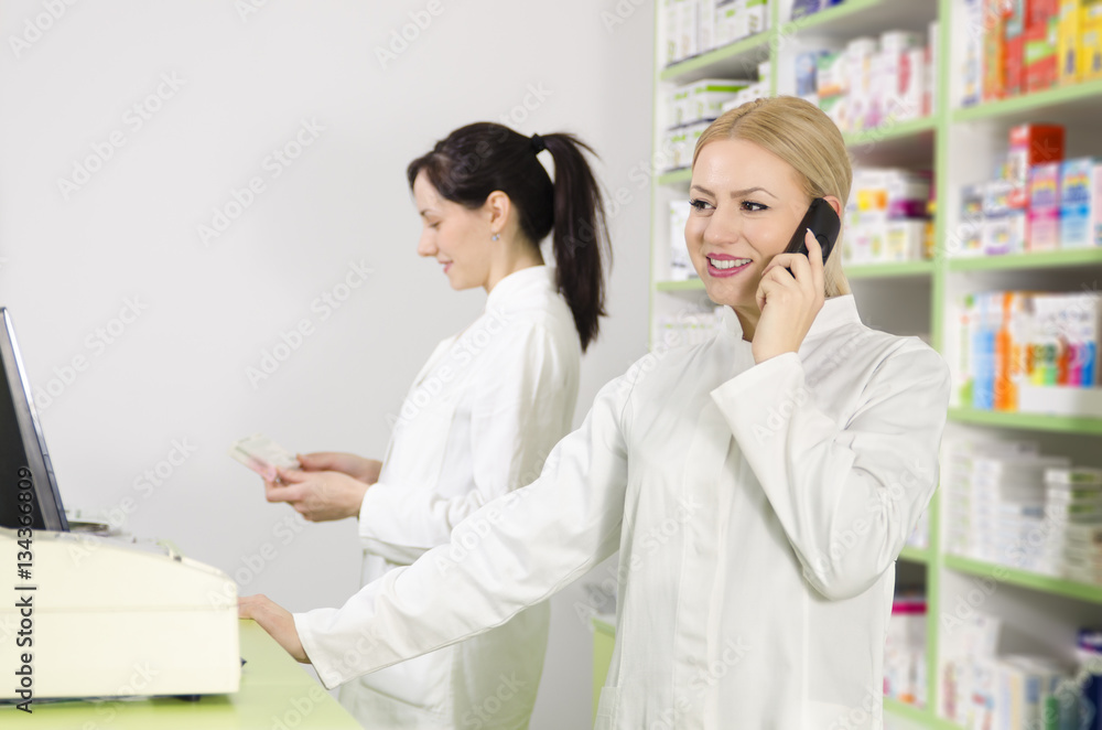Beautiful female pharmacist talking to the phone with client