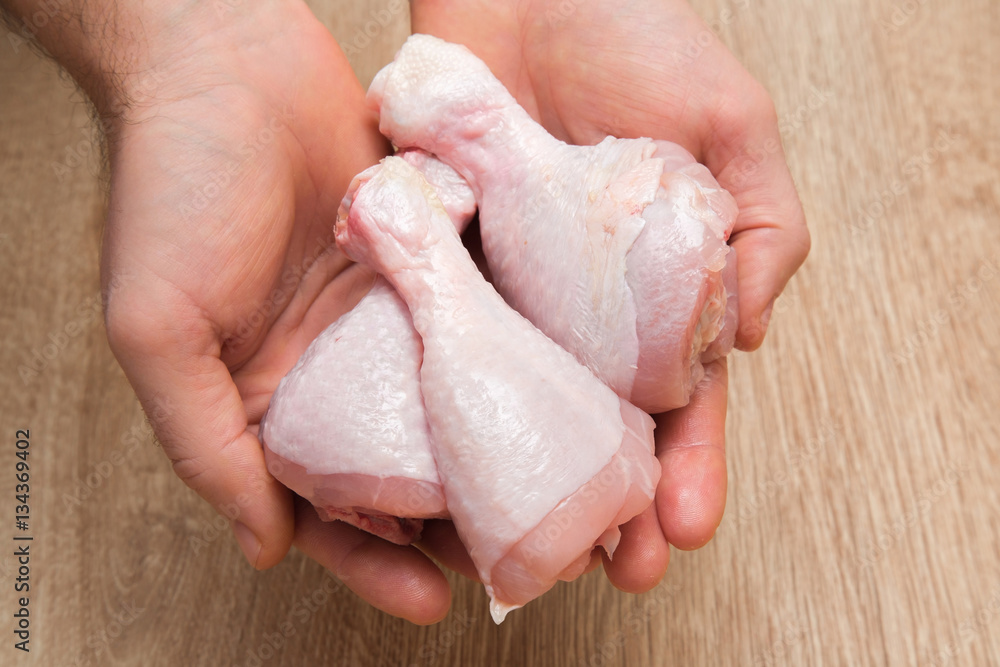 Man's hand holding a chicken meat in the kitchen. Cooking at home. Healthy eating and lifestyle. Man's hand holding a chicken meat in the kitchen. Cooking at home. Healthy eating and lifestyle.