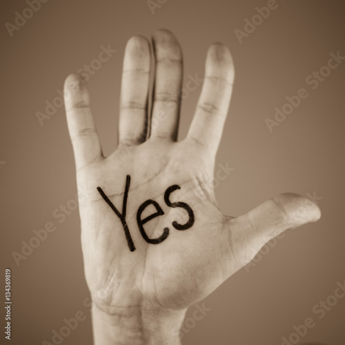 man showing the word "yes"written on the palm of a his hand