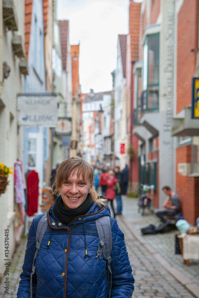 Young smiling woman tourist smiling with colorful houses in historic Schnoorviertel in Bremen, Germany at the background