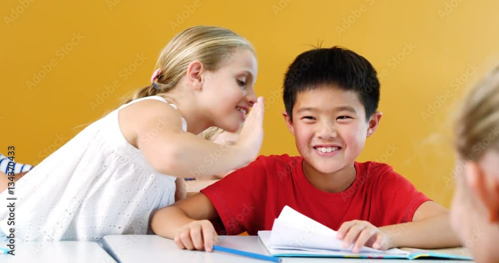 Schoolgirl whispering into his friend s ear in classroom at school 4k