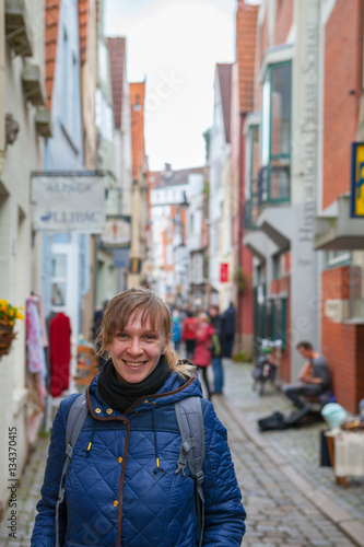 Young smiling woman tourist smiling with colorful houses in historic Schnoorviertel in Bremen, Germany at the background © yegorov_nick