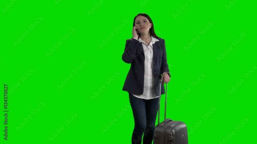 Happy woman traveling with suitcase waving her hand against green screen Happy woman traveling with suitcase waving her hand against green screen