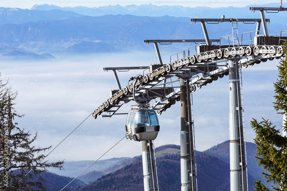 Ski lift cable booth or car, Ropeway and cableway transport system for skiers with fog on valley background.