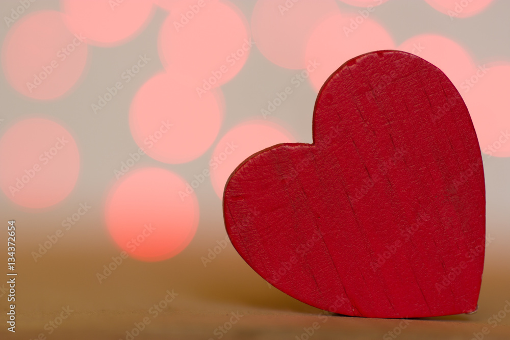 One red wooden heart on blurred background One red wooden heart on blurred background