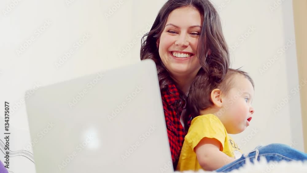 Happy young family sitting on the sofa using laptop together at home in living room Happy young family sitting on the sofa using laptop together at home in living room