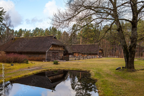 View of the rustic farm building near small pond. Wooden architecture of North and Baltics