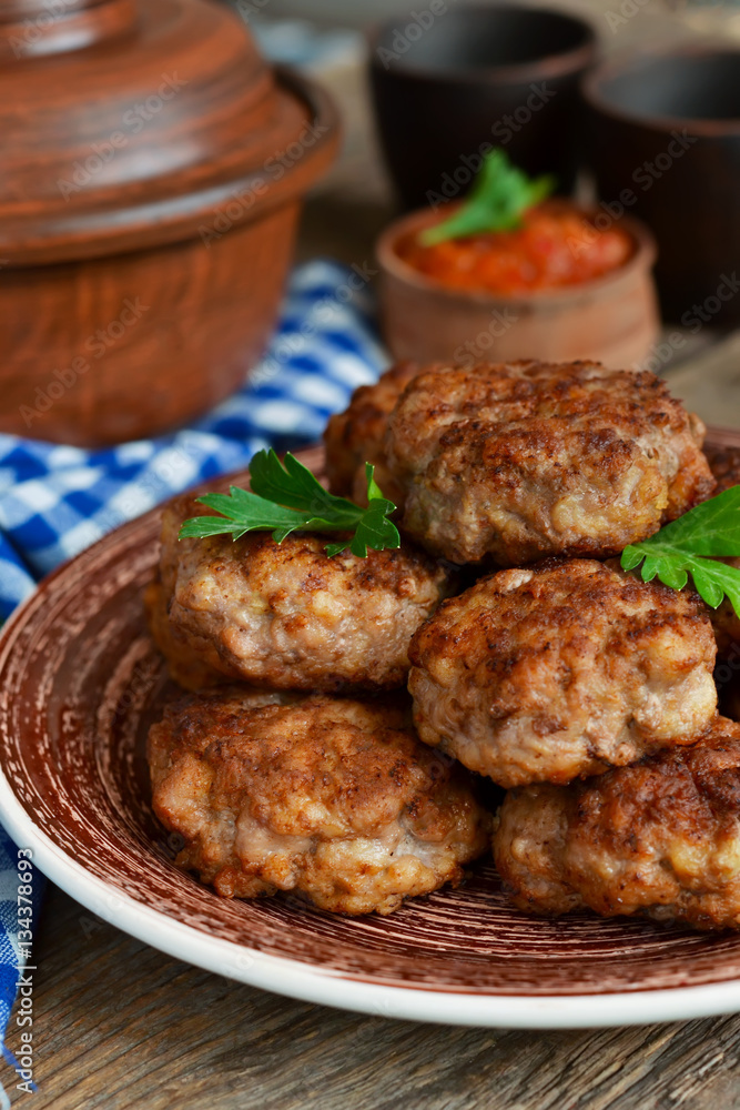 Homemade meatballs with meat and onions on a wooden background.