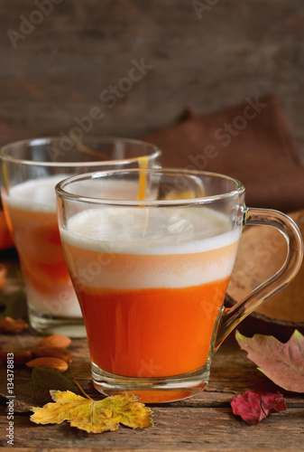 Home latte with milk, almonds and pumpkin on a wooden background