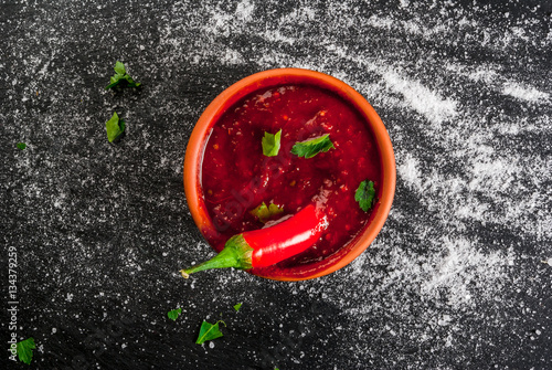 Hot Tabasco sauce in a bowl, top view. With ingredients - a slice of hot pepper and salt, copy space