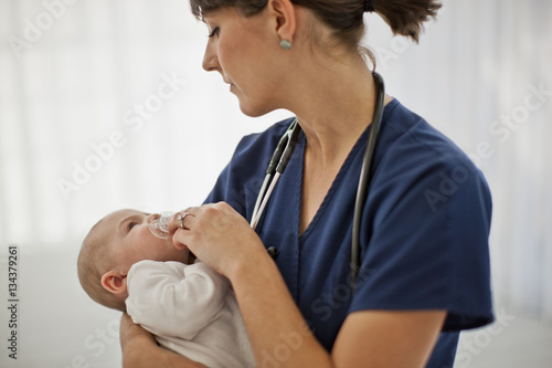 Young nurse carrying a baby boy in her arms