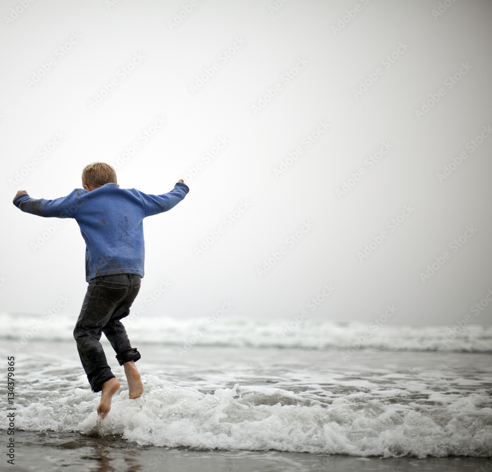Small boy jumping in shallow water at beach. Small boy jumping in shallow water at beach.
