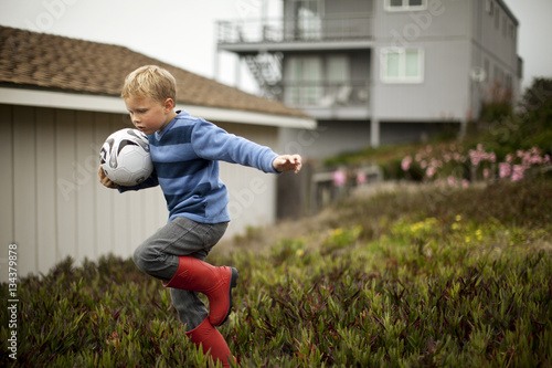 Boy holding soccer ball while playing outdoors