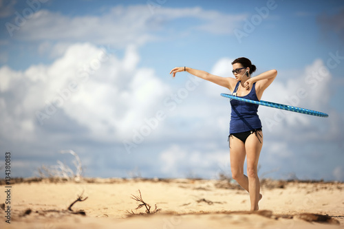 Young woman using a hula hoop at the beach.