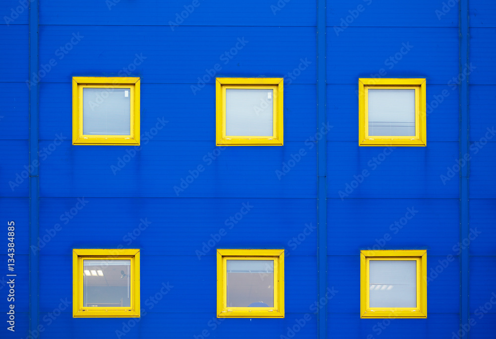 Facade of a modern blue warehouse and six yellow windows