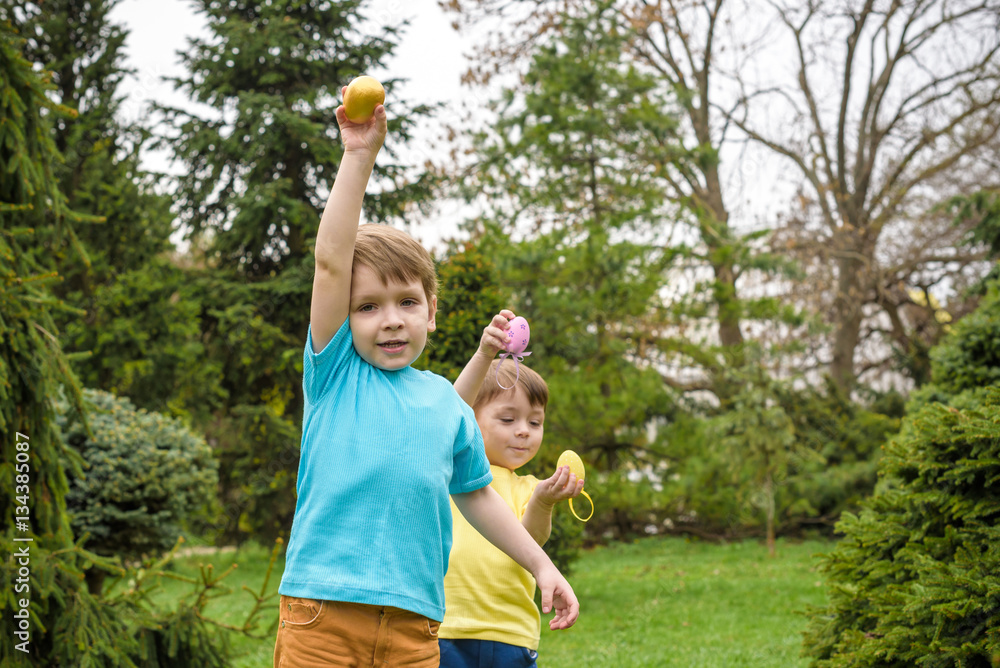 Obraz premium Kids on Easter egg hunt in blooming spring garden. Children sear