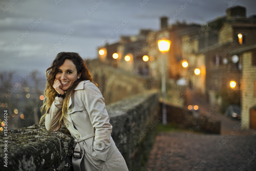 Portrait of a smiling young woman leaning on a stone wall at dusk. Portrait of a smiling young woman leaning on a stone wall at dusk.