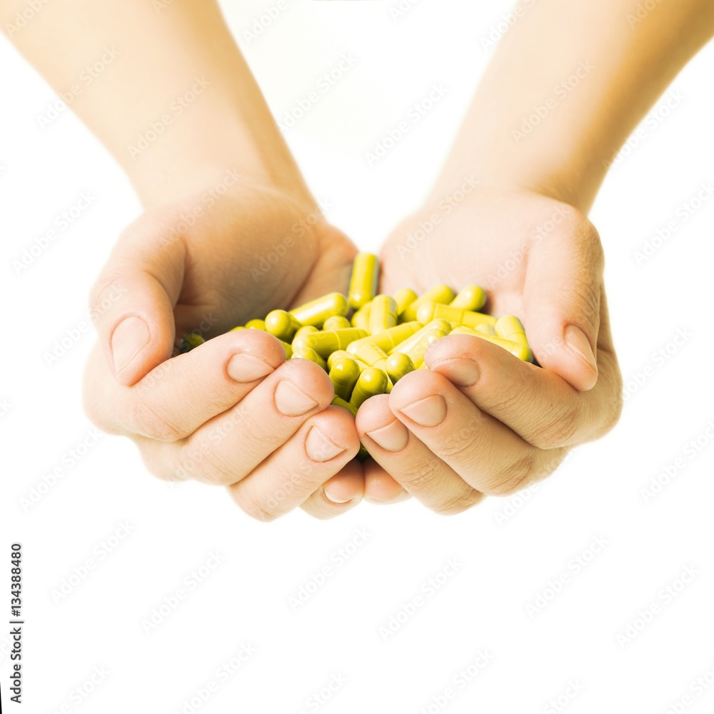 Hands is giving yellow capsules and orange pills on white background. Hands is giving yellow capsules and orange pills on white background.