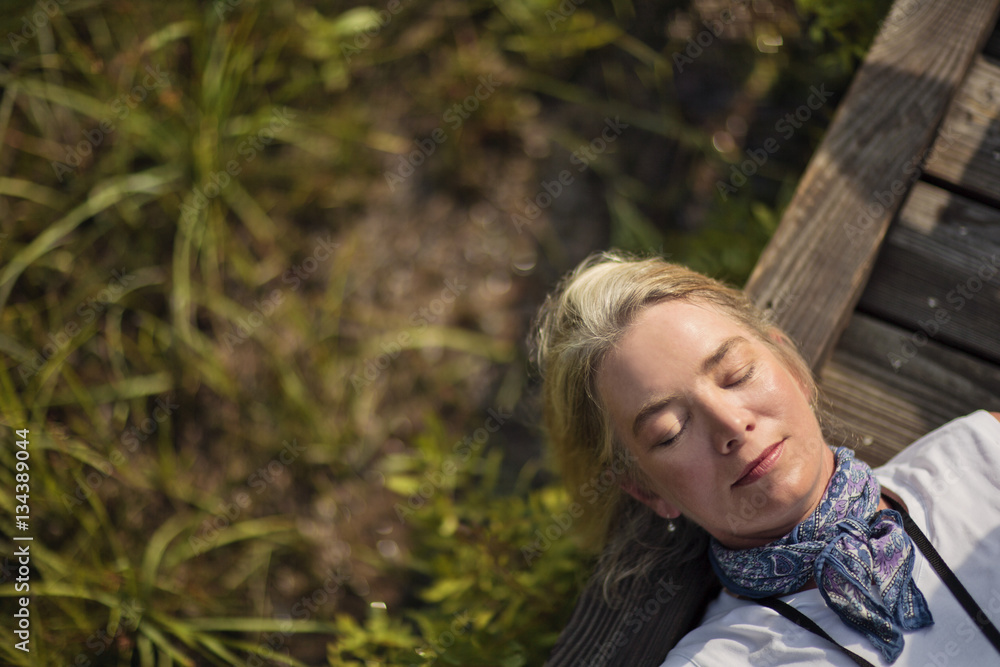 Woman lying down and resting on wooden forest walkway. Woman lying down and resting on wooden forest walkway.
