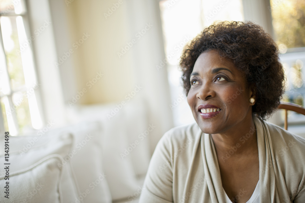 Smiling middle aged woman sitting in her living room. Smiling middle aged woman sitting in her living room.