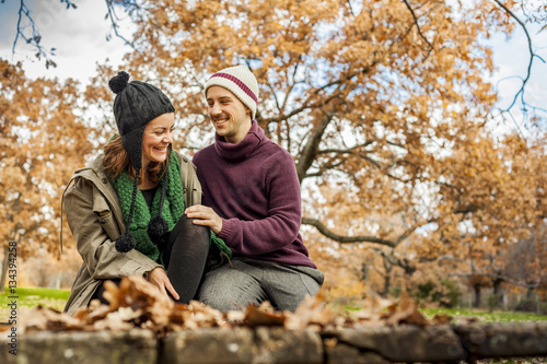 Lovely young couple talking, sit in a bench in the park in autum