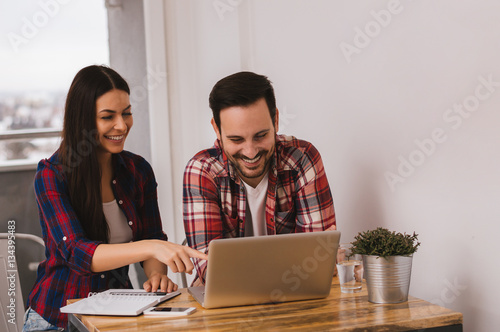 A beautiful young couple sitting at a Table and working on compu