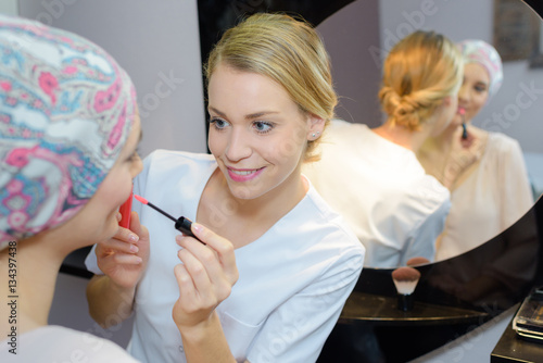 Fotografia Beautician applying lipgloss to client