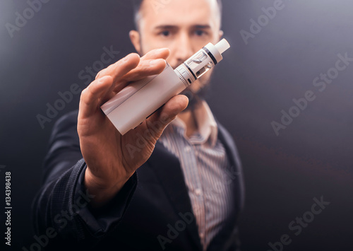 Photos Vaping device in in the man's hand. Electronic cigarette, vape