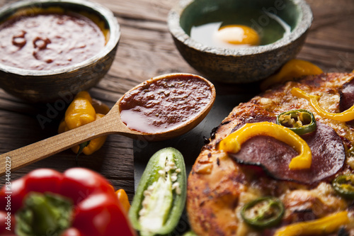 Tasty pizza, tomatoes and others ingredients on a wooden backgro