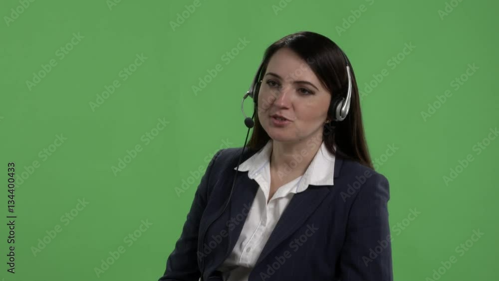 Call center worker with headset takes phone call against green screen Call center worker with headset takes phone call against green screen