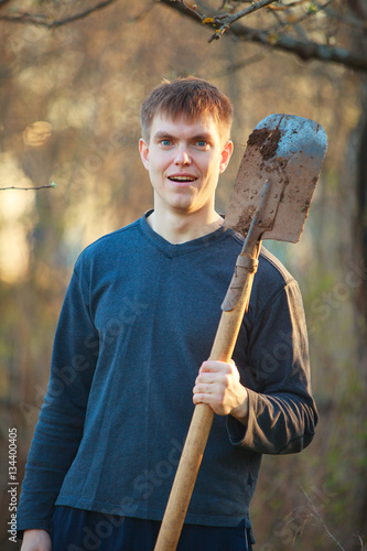Agronomist handsome strong man with shovel on background of flo