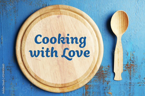 Cooking with love concept. Cutting board and spoon on blue wooden background