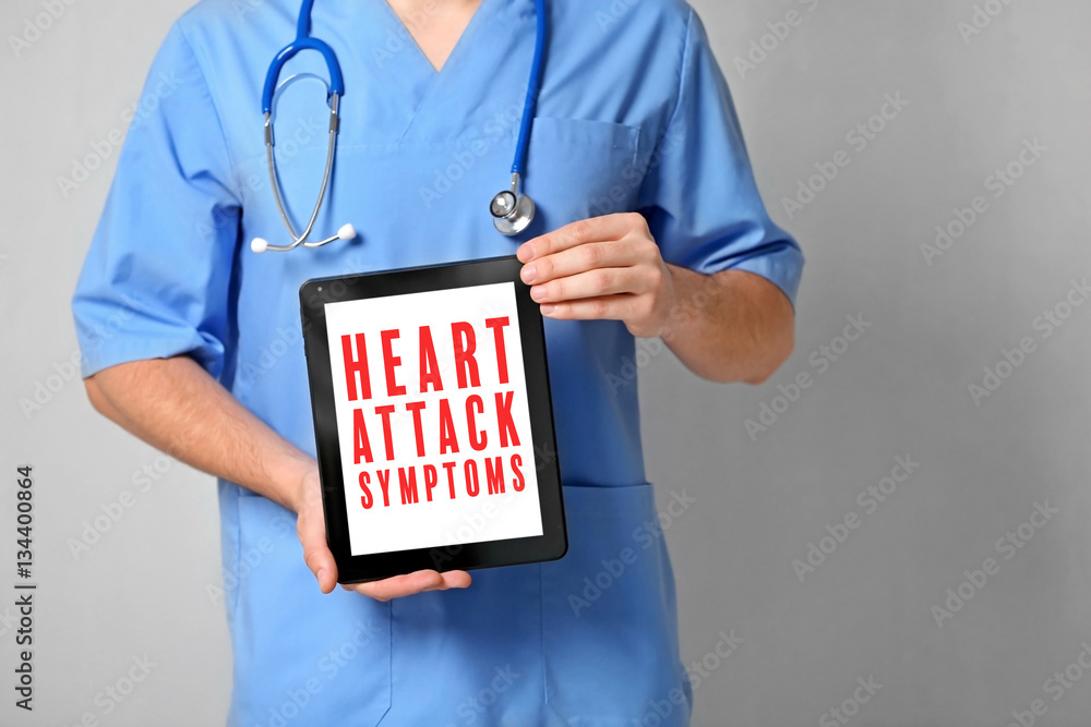 Cardiology and health care concept. Doctor's hands holding tablet with text HEART ATTACK SYMPTOMS Cardiology and health care concept. Doctor's hands holding tablet with text HEART ATTACK SYMPTOMS