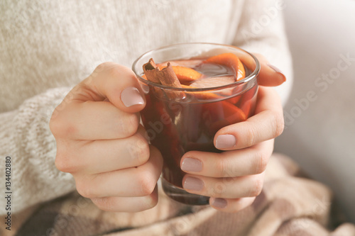 Woman holding glass cup of delicious Christmas mulled wine in hands, closeup