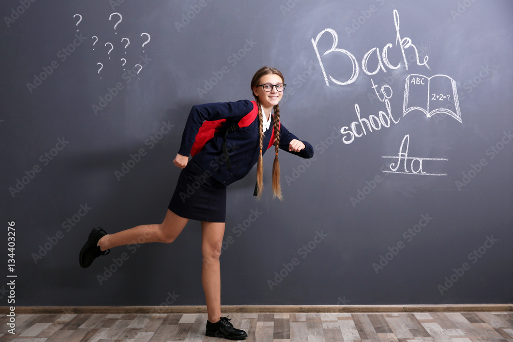 Girl with backpack standing near school blackboard Girl with backpack standing near school blackboard