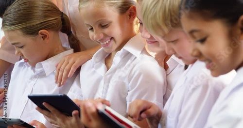 Teacher teaching kids on digital tablet in classroom at school 4k